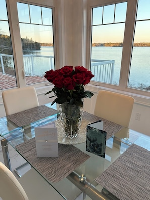 A table with a glass top, a vase with red roses, a card, and a card with a deer image.