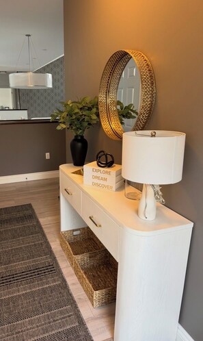 A white console table with a mirror, a lamp, and a sign with motivational words.