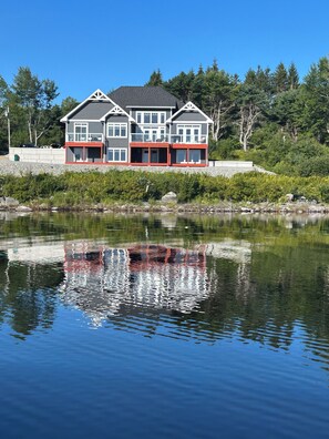 A multi-story house with a balcony, located near a body of water.