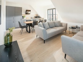 Un loft moderno con comedor, kitchenette y sala de estar con sofá y mesa de centro.