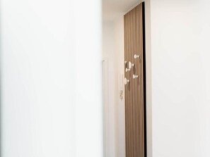 Una puerta blanca con panel de madera vertical y una manija moderna.