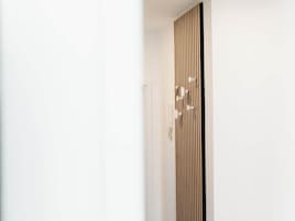 Una puerta blanca con panel de madera vertical y una manija moderna.