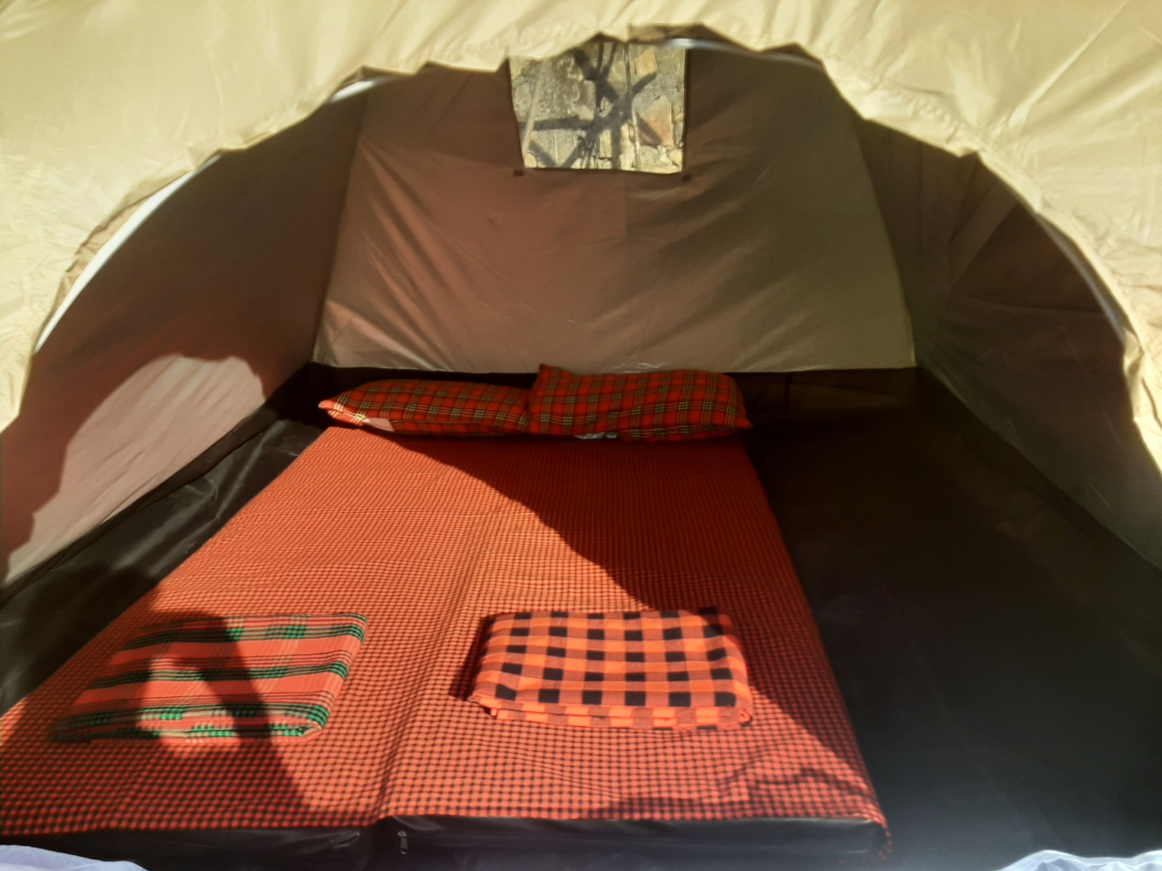 Een tent met een bed, kussens en een deken.