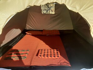 Een tent met een bed, kussens en een deken.