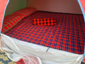 A tent with a bed inside, featuring a plaid bedding pattern. - Olympos Camping (Morogoro)