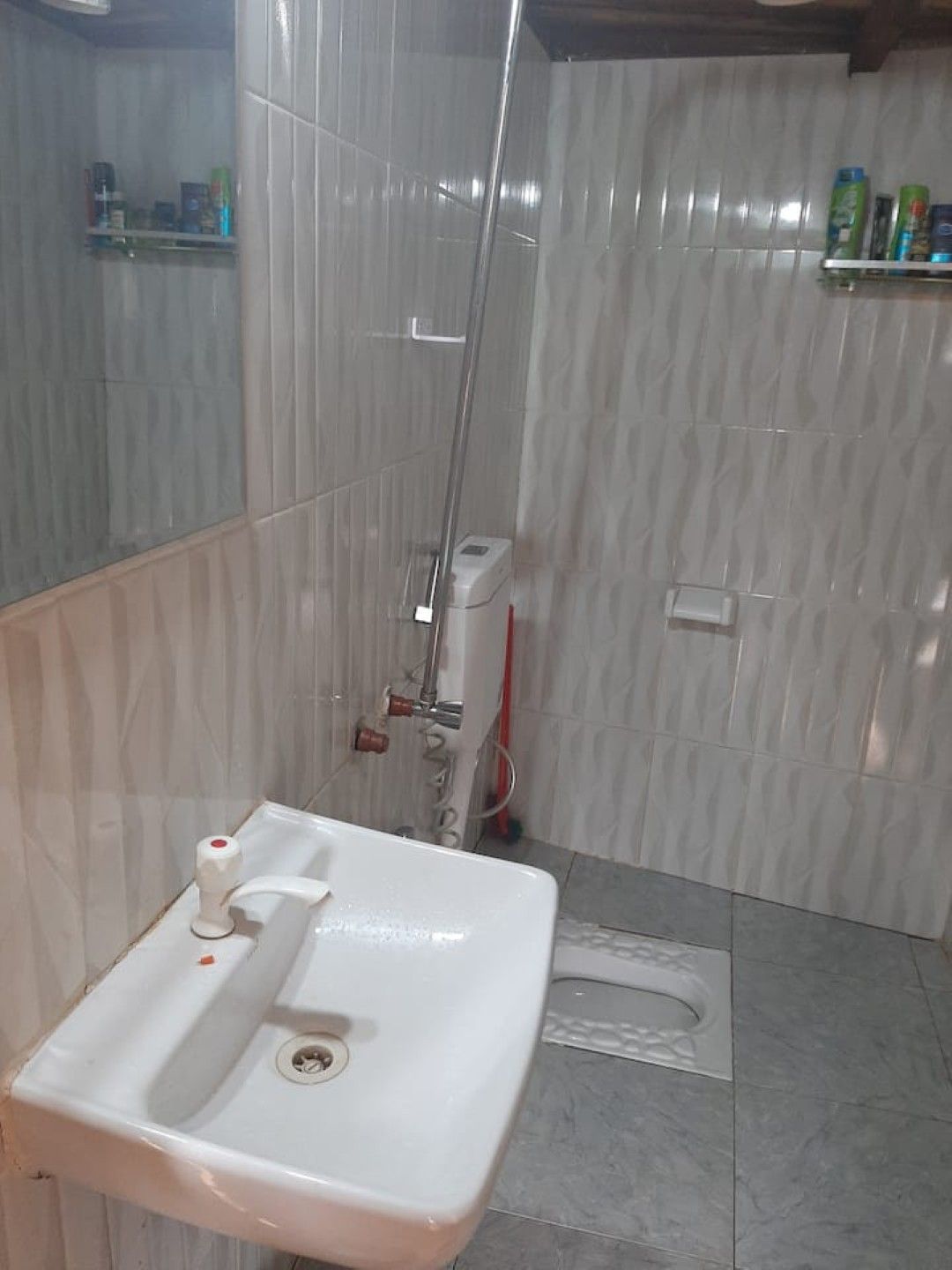 A bathroom with a white sink, a shower, and tiled walls.