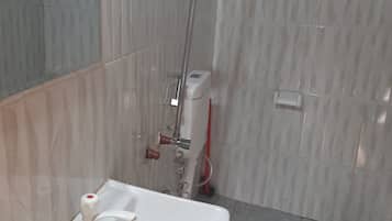 A bathroom with a white sink, a shower, and tiled walls.