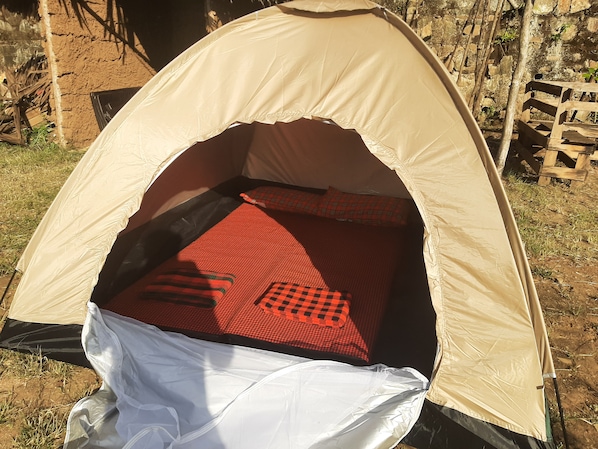 A tent with a sleeping area inside, including a bed and pillows.