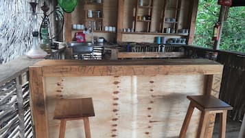 Eine Holztresorecke mit Hockern, einem Spülbecken und Regalen mit verschiedenen Gegenständen.
