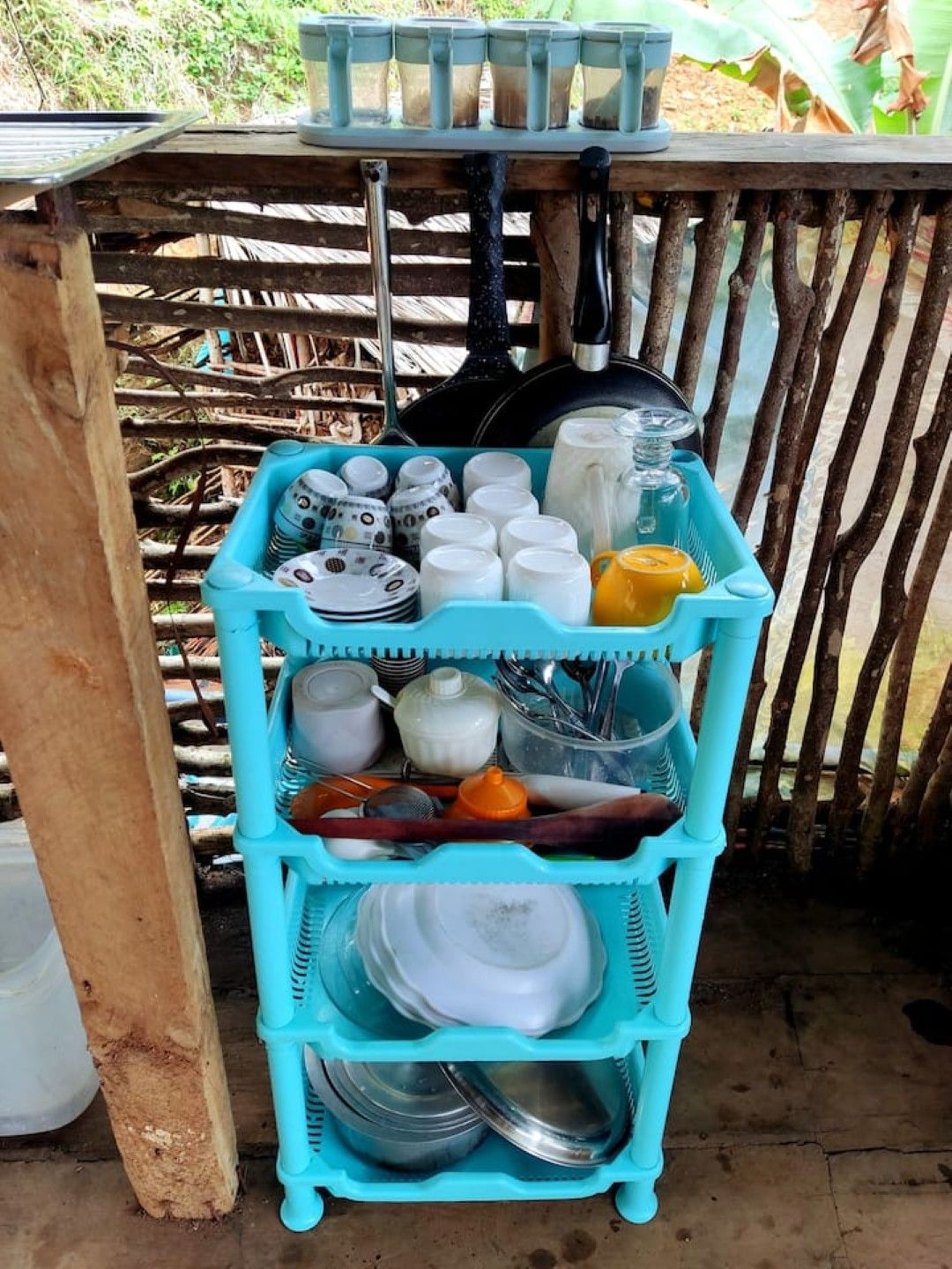 A blue plastic shelf with various kitchenware items.