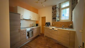 Une cuisine équipée d’une cuisinière, d’un four et d’un lave-vaisselle, avec des meubles en bois et un mur d’accent en pierre.