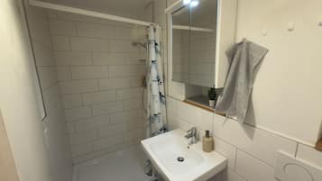 Ein Badezimmer mit Dusche, Waschbecken und Spiegel.