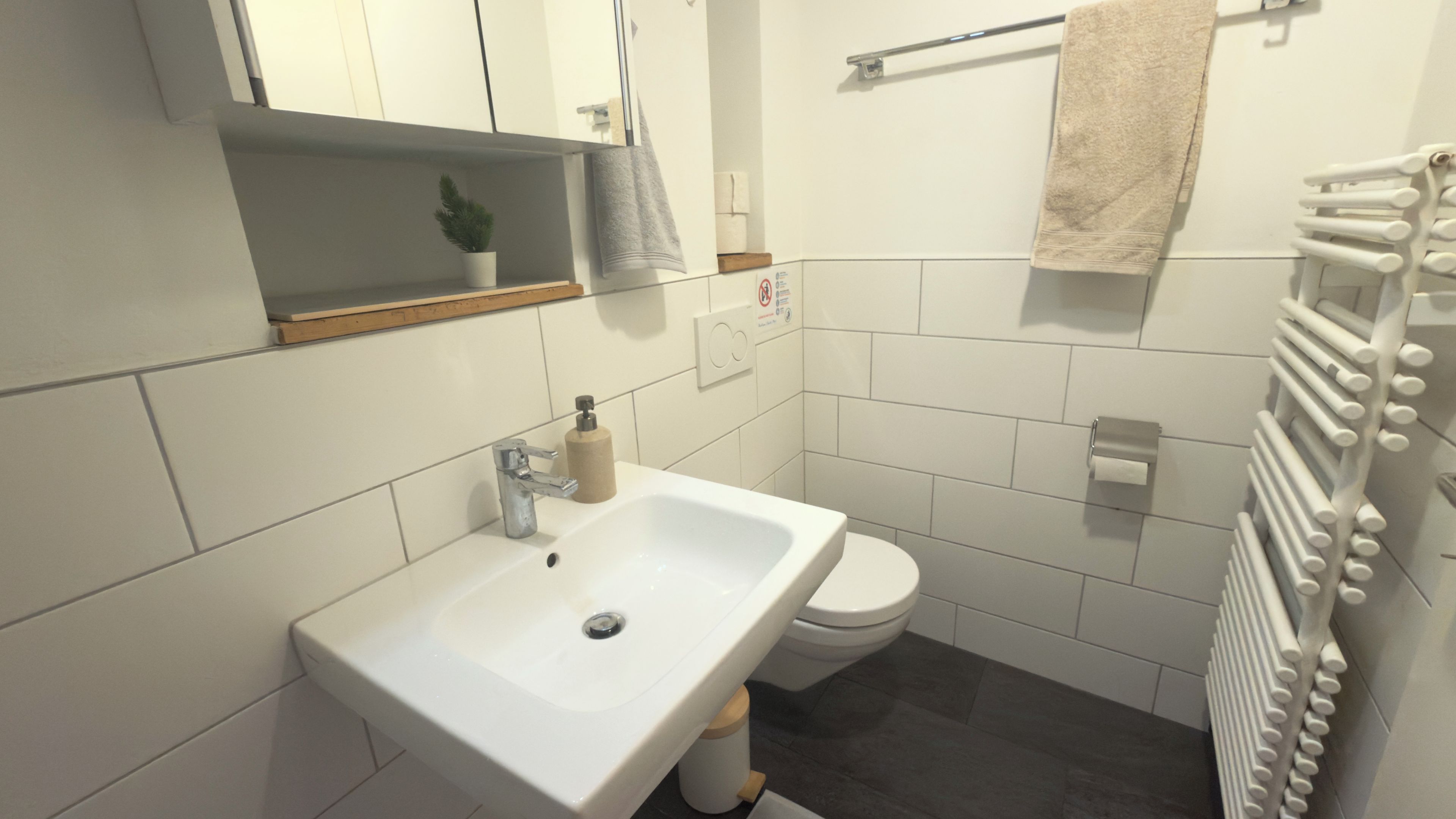 Un baño moderno con lavamanos, inodoro y toallero blancos.