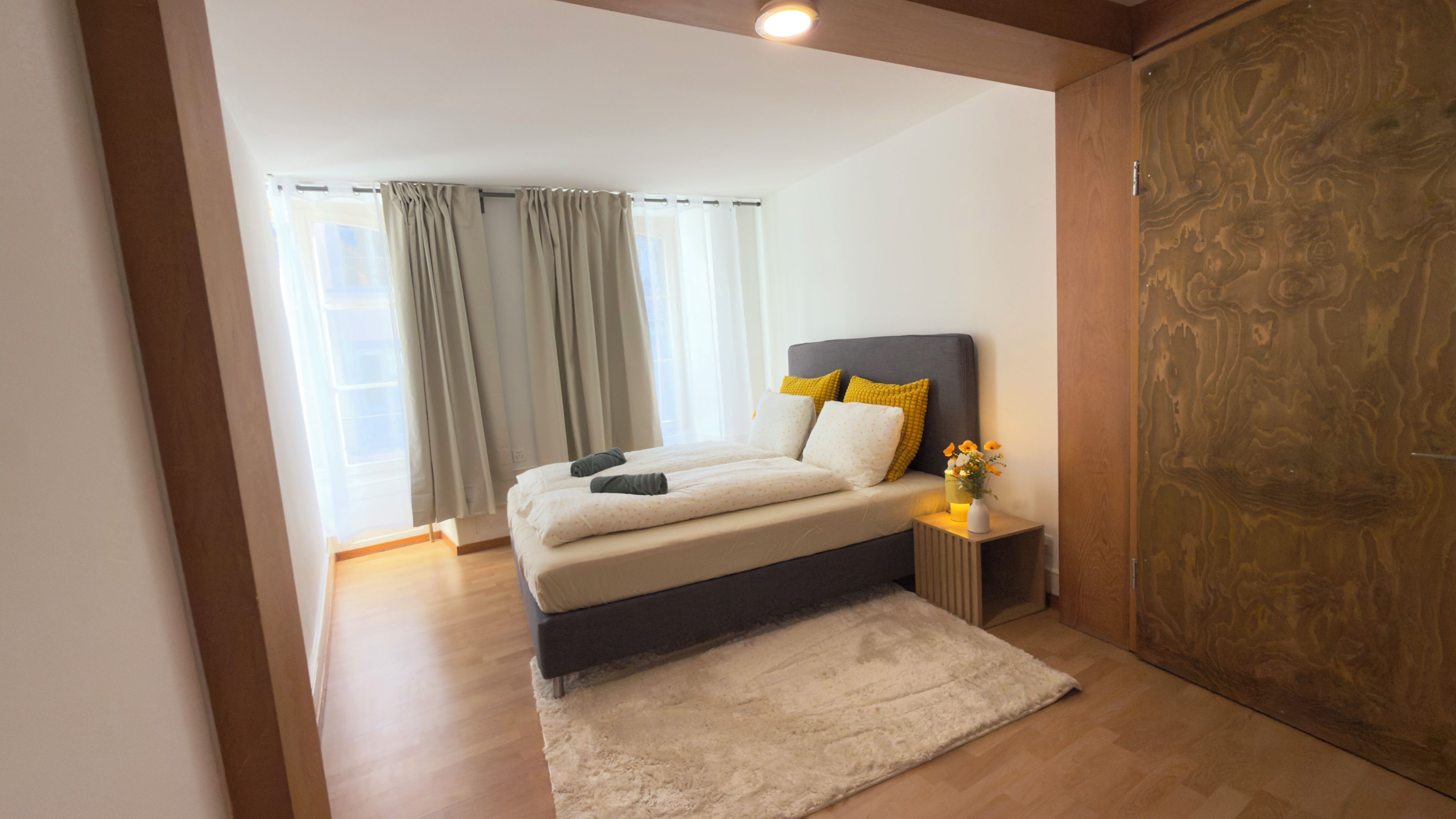A bedroom with a bed, bedside table, and a wardrobe.