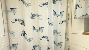 Casa de banho com cortina de chuveiro estampada com pássaros, uma pia branca e um espelho sobre a pia.