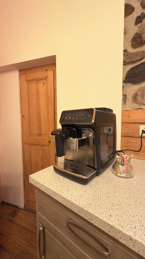 Une cuisine équipée d’une machine à café, d’une porte en bois et d’un plan de travail.
