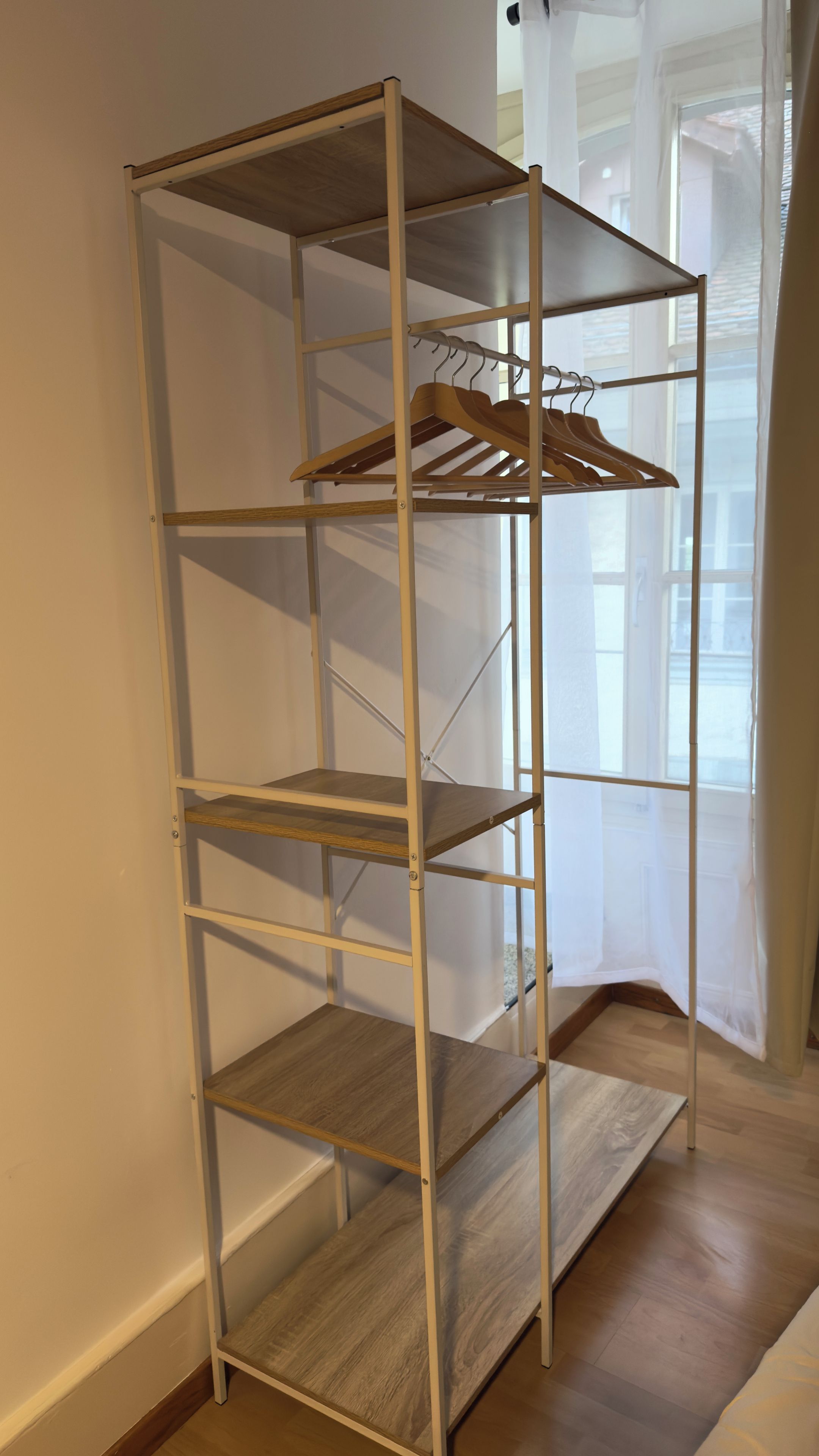 A metal shelving unit with wooden shelves and a wooden hanger rack.