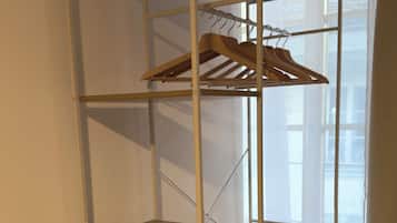 A metal shelving unit with wooden shelves and a wooden hanger rack.