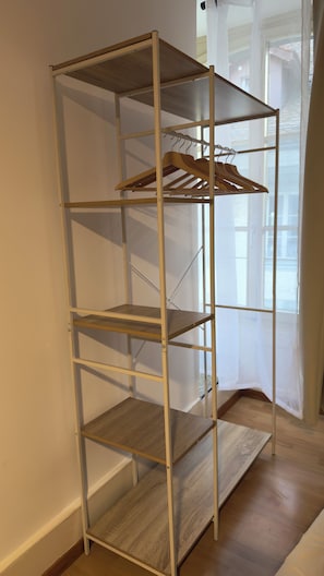 A metal shelving unit with wooden shelves and a wooden hanger rack.