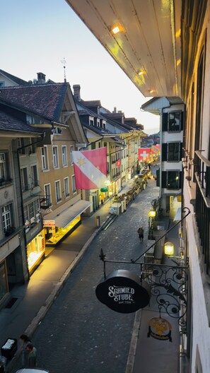 A street view with buildings, a flag, and a sign for 'Schmied Stube Bar Thun'. - Thun Arcades I Old Town I Free Parking IWifi |Alps (Thun)