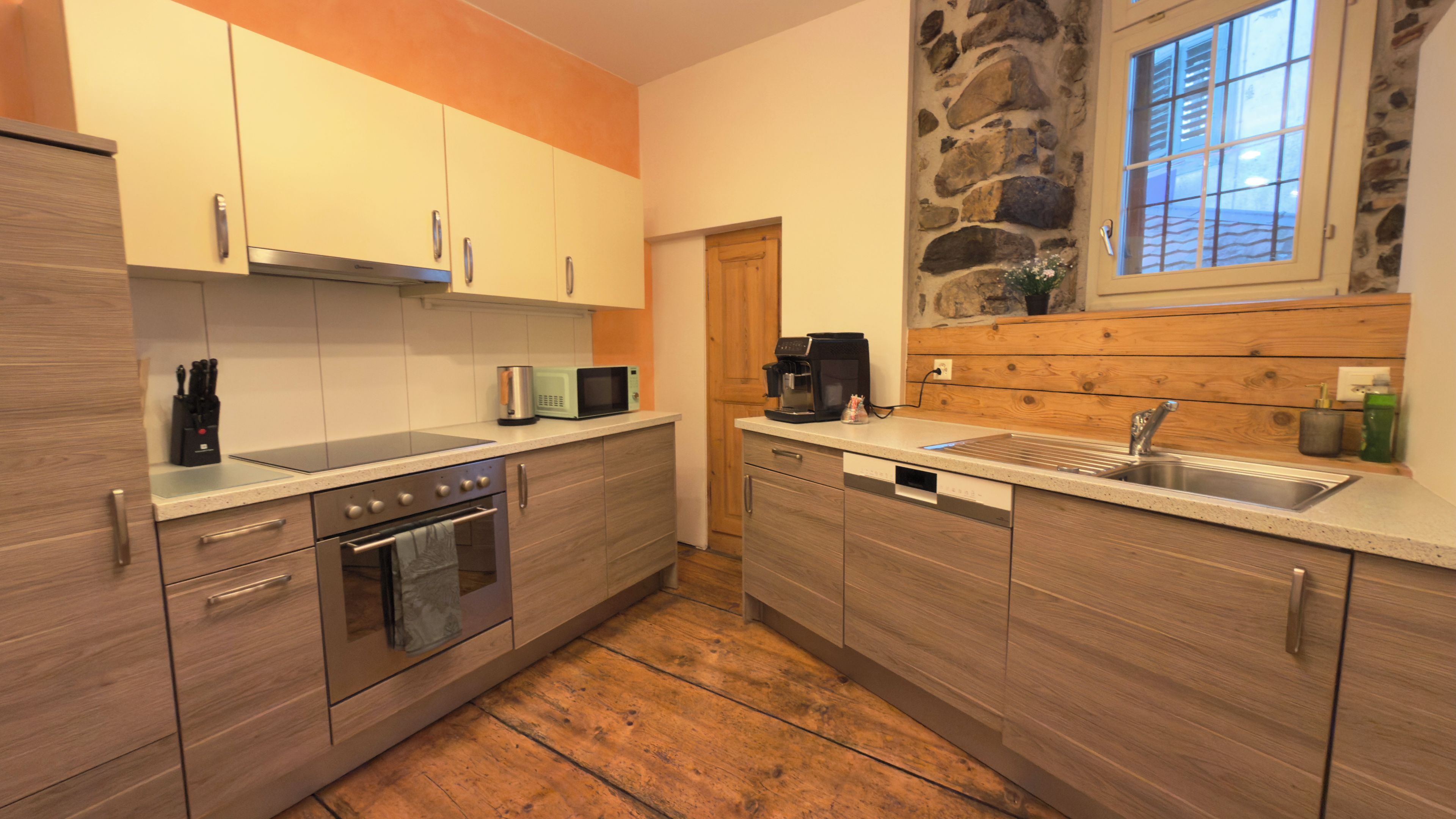 A kitchen with wooden cabinets, a built-in oven, a microwave, and a coffee maker.