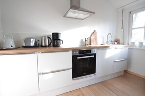 A modern kitchen with white cabinets, a built-in oven, a coffee maker, and a toaster. - Vacation Rental in the Countryside Near Bremen – 90 square meters for up to 5 people (Ritterhude)