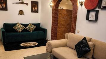Ein Wohnzimmer mit einem grünen Sofa, einem beigen Sofa und einem Couchtisch mit einer dekorativen Schale.