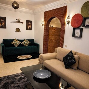 Ein Wohnzimmer mit einem grünen Sofa, einem beigen Sofa und einem Couchtisch mit einer dekorativen Schale.