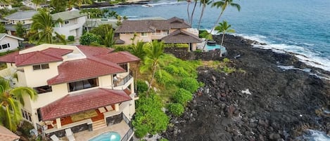 A coastal property with a swimming pool, a rocky shoreline, and a view of the ocean.