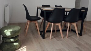 Et spiseområde med et træbord, sorte stole og et vægur.