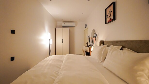 Ett hotellrum med en stor säng, ett sängbord, en spegel och en luftkonditioneringsanläggning på väggen.