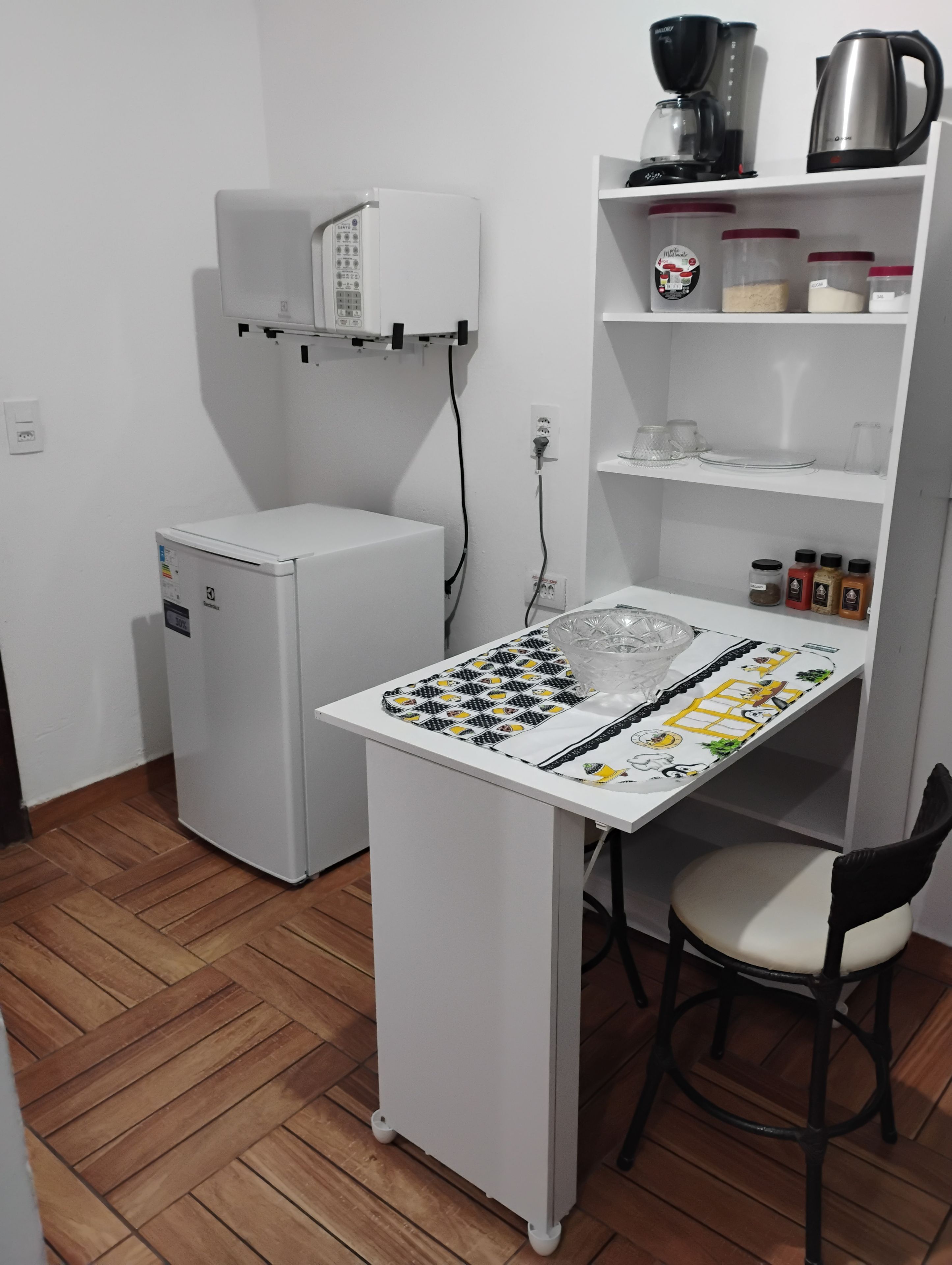 Un angolo cottura compatto con frigorifero, forno a microonde e macchina per il caffè.
