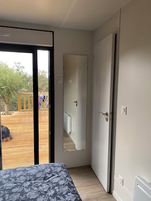 Une chambre avec un lit, une porte et une vue sur une terrasse en bois à l’extérieur.