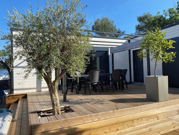 Un espace extérieur aménagé en terrasse, avec une plateforme en bois, une table et des chaises, et une structure en forme de pergola.