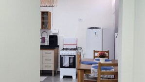 Een praktische keuken met een gasfornuis, een koelkast en een eethoek met een tafel en stoelen.