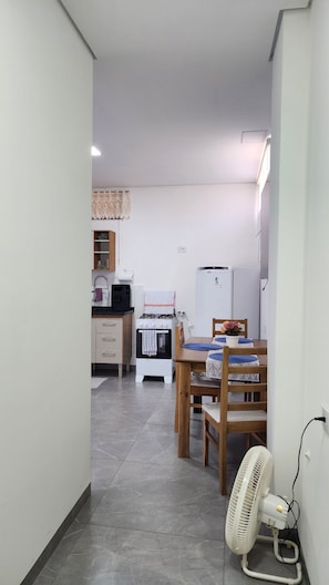 Cozinha compacta com fogão a gás, geladeira e área de refeições com mesa e cadeiras.