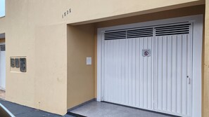 A closed white garage door with a no parking sign, a utility box, and a number '1525' on the wall.