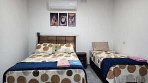 Een hotelkamer met een bed, nachtkastje en een wandairconditioner.