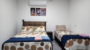 Quarto de hotel com cama, mesa de cabeceira e ar condicionado fixado na parede.