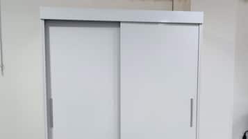 Ein weißer Kleiderschrank mit mehreren Schubladen und ein Holzstuhl.