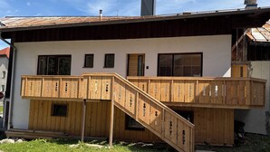 Una casa de madera de dos pisos, con un balcón y una escalera.