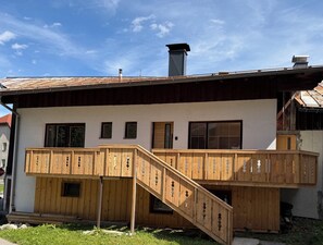Una casa in legno a due piani con un balcone e una scala.