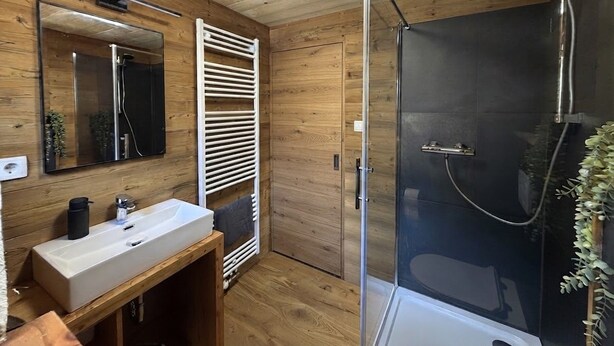 Un baño con paneles de madera, un lavabo, un espejo y una cabina de ducha.