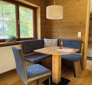 Un interno in legno con una panchina, un tavolo e una lampada a sospensione.