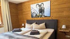 Habitación con paneles de madera, una cama, almohadas, una manta y una lámpara.