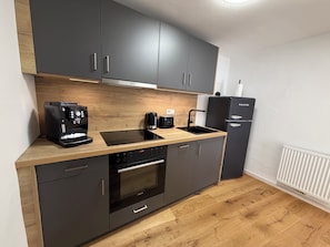 A modern kitchen with a built-in oven, a coffee machine, and a refrigerator.
