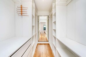 Una cabina armadio stretta con scaffali bianchi e pavimento in legno.