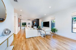 Un'ampia zona giorno con un divano bianco, un tavolino da caffè e una TV a parete.