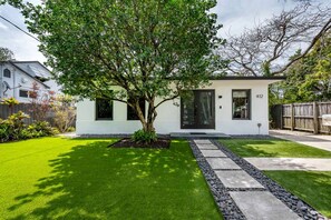 Een modern, tweelaags huis met een verzorgd gazon en een boom in de voortuin.