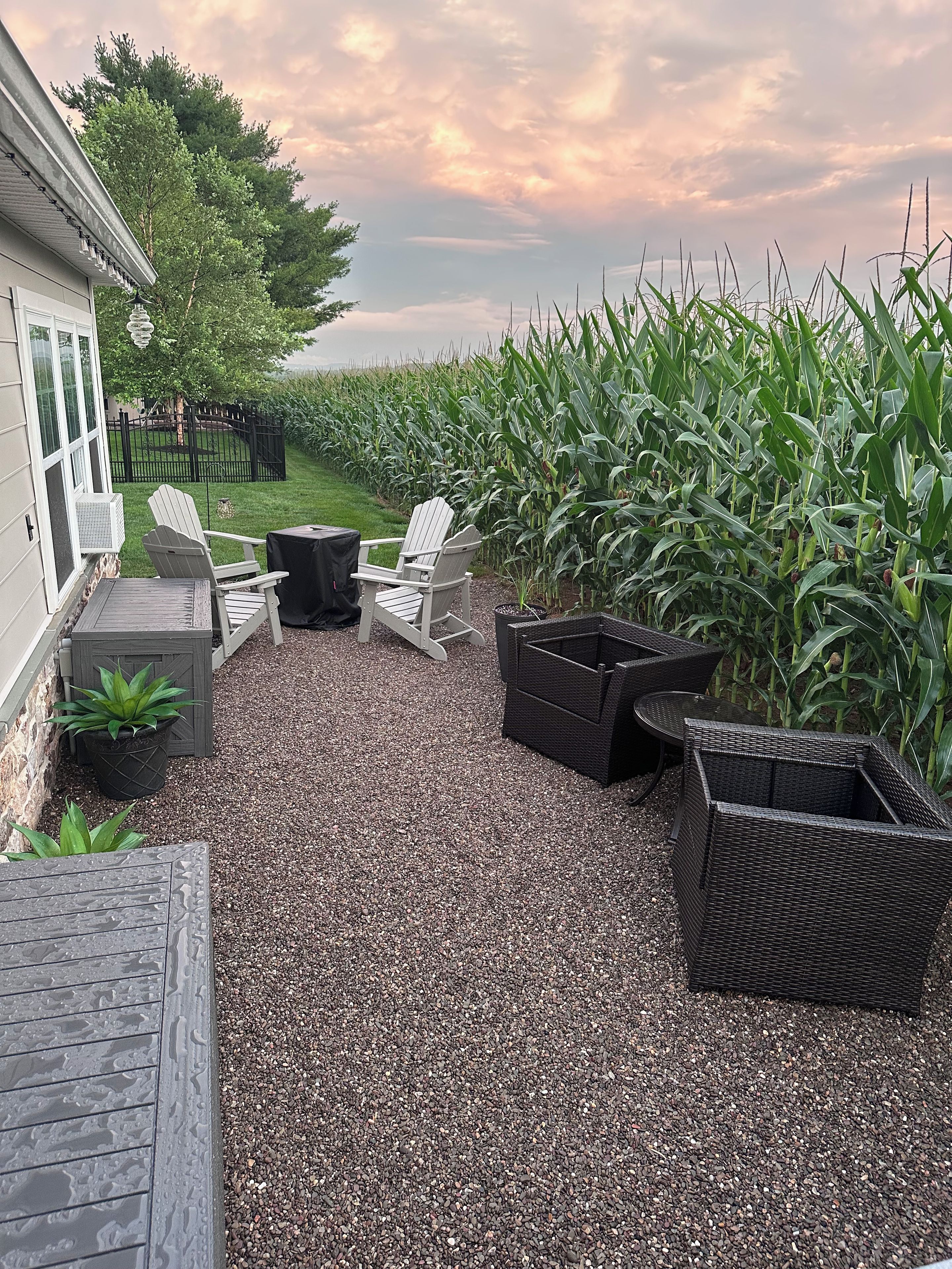 A patio area with Adirondack chairs, a table, and a black wicker planter.